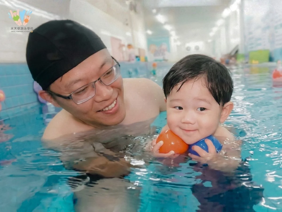 水天使游泳學校的親子共游課程，爸爸與寶寶在泳池中一起玩彩色球，增進親子親密度。