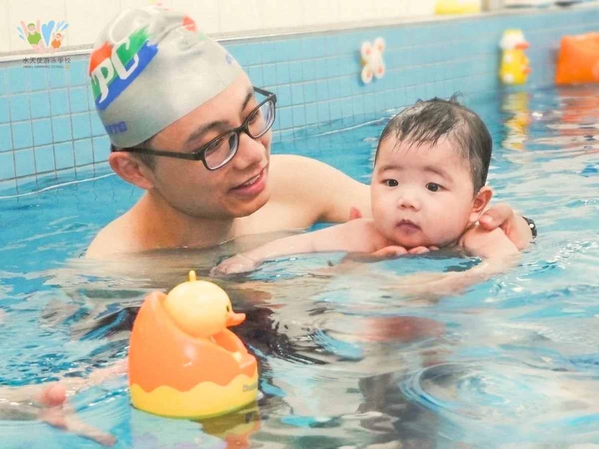 嬰兒在水天使游泳學校練習水性，專注看著水面上的小黃鴨玩具，透過視覺刺激引發游泳興趣。